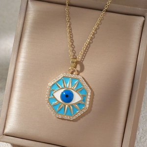 Gros plan sur le pendentif œil porte-bonheur octogonal doré en émail et cristaux