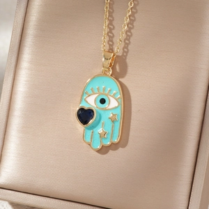 Golden Hamsa Hand necklace with blue enamel evil eye and heart gem in a jewelry box