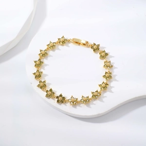 Eleganteres goldfarbenes Armband mit grünen Zirkonblüten auf weißem Displaystein