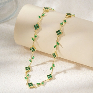 Elegant gold clover flower necklace with emerald green gemstones and leaf design