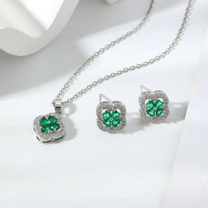 Macro shot of silver clover necklace and earrings set with emerald green zircon stones