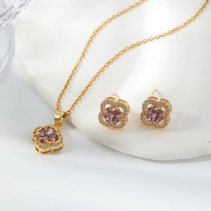 Macro detail of gold clover jewelry set with purple heart-shaped zircons and white crystals