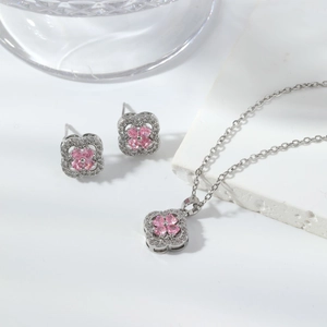 Macro shot of silver clover necklace and earrings set with pink heart stones and white crystals
