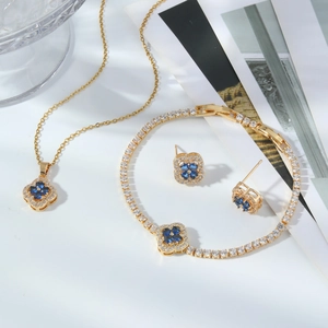 Detail of four-leaf clover jewelry set with blue stones and gold-plated tennis chain