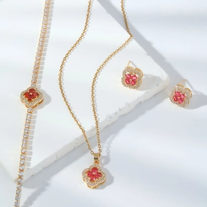 Elegant gold clover jewelry set featuring red zircon stones and sparkling crystals