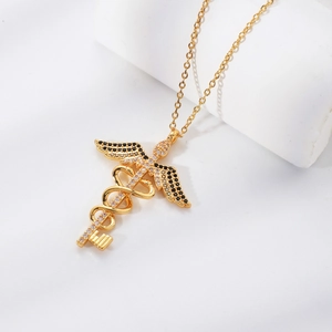 Gold winged caduceus key pendant necklace with black and white gemstones on a white stand