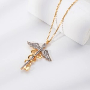 Golden Caduceus angel wing key pendant necklace with white zircons on a white display