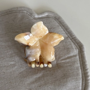 Detail of frangipani hair claw with cream and amber marble texture on linen surface