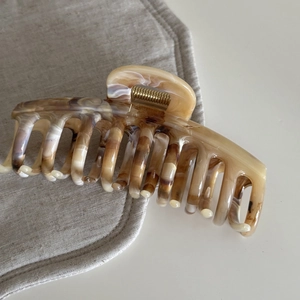 Macro detail of amber marbled acetate hair claw clip with a strong golden metal spring