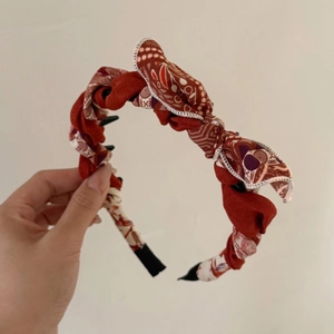 Dettaglio del cerchietto floreale rosso con dentini interni neri per fissare l'acconciatura