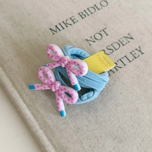 Detail view of pink polka dot resin bows and floral hair ties on a beige book