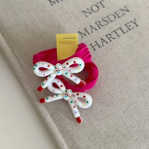 Detail of two pink floral elastic hair ties with polka dot bow pendants on a book