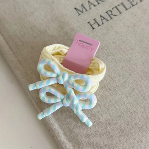 Close-up of pastel yellow elastic hair ties with colorful striped resin bows