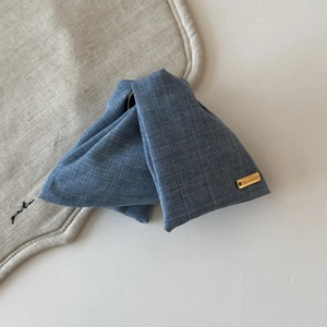 Nahaufnahme der blauen Denim-Schleifen-Haarklammer mit goldenem Logo auf Textil