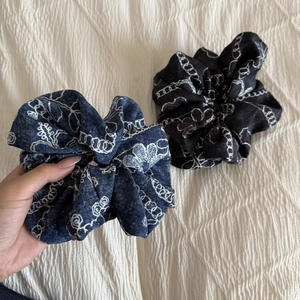 Detail view of oversized denim blue and black scrunchies with floral and chain prints