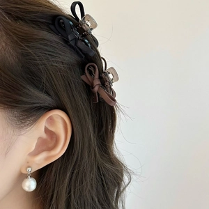 Détail de pinces à cheveux à nœud noir élégant et boucles d'oreilles perles assorties