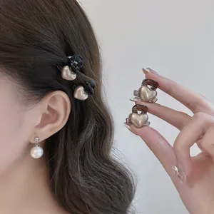 Detail of mini heart hair clips in pearl gold and black colors for side fringe styling
