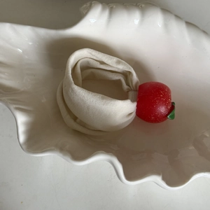 Close-up of a cream elastic scrunchie featuring a red apple charm with green leaves