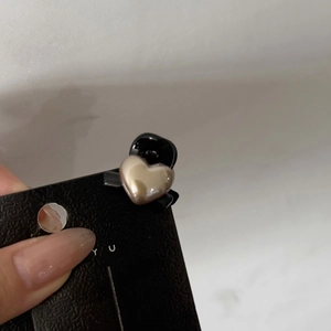 Close-up of mini hair clip featuring a golden heart pearl on a black resin base