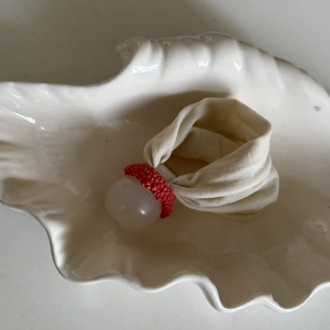 Cute tangerine style off-white elastic hair tie with red crochet detail on white shell plate