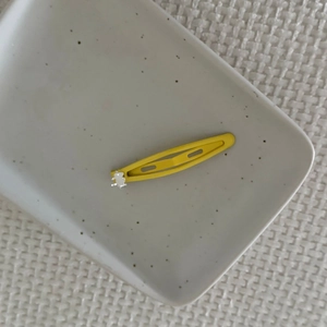 Macro detail of yellow drip oil metal hair clip with a cute translucent resin bear decoration