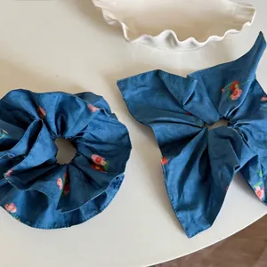 Dual set of dark blue floral scrunchies featuring a long-tail bow in rustic cotton fabric