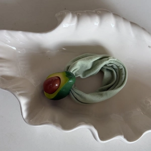 Detail of cute avocado hair tie with green ruffled fabric and resin fruit charm