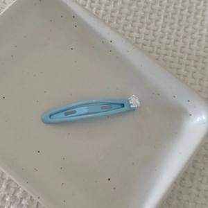 Detail view of light blue sugar-shaped drop oil hair clip with clear crystal accent