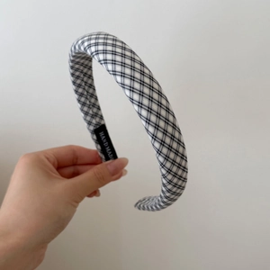 Detailed close-up of a sponge headband with black and white plaid and a Hand Made label