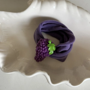 Detail view of a soft purple knitted headband featuring a 3D grape design and green leaf detail