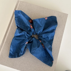 Detail view of large navy blue floral scrunchie with soft fabric texture on a book