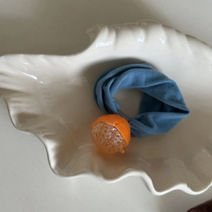 Close-up of blue fabric hair tie featuring a detailed resin peeled orange charm
