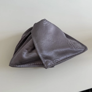 Detailed close-up of dark grey satin fabric with embossed rose floral pattern and fine texture