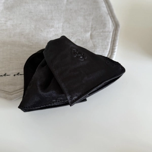 Detail of black satin fabric with floral embossed texture on a triangular hair claw clip