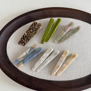 Set of 12 acetate hair clips with marble patterns in a wooden tray detail view