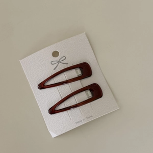 Close-up of deep burgundy tortoiseshell BB hair clips on white embossed display card