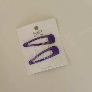 Close-up of a pair of purple teardrop BB hair clips on a white display card