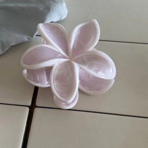 Dettaglio del motivo marmorizzato rosa sulla molletta per capelli a forma di plumeria
