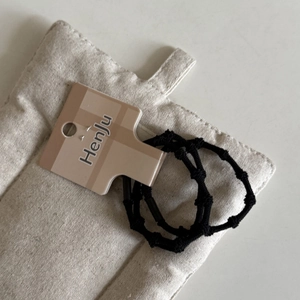 Close-up of black braided elastic hair ties with textured knots and cardboard tag