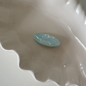 Macro shot of a light blue oval hair clip with sparkling white sequins in a white dish