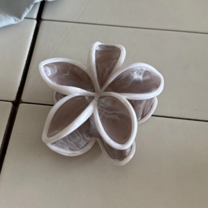 Dettaglio della pinza per capelli in acetato a forma di fiore con motivo marmorizzato e bordi bianchi