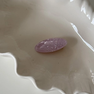 Detail of a purple translucent glitter resin hair clip displayed on a white plate
