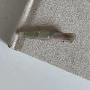 Detailed close-up of a handmade acetate hair clip with green marble texture on linen