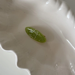 Detailed macro view of matcha green oval hair clip with white shimmering flakes