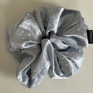 Detailed view of grey blue satin polka dot scrunchie with fashion woven label tag