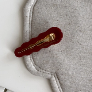 Dettaglio del fermaglio per capelli rosso ondulato con scritte francesi sulla molla