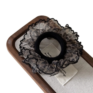 French leopard print mesh scrunchie with lace trim on a minimalist display tray