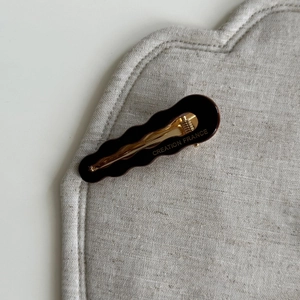 Dettaglio macro della clip per capelli in acetato tartarugato con base dorata incisa