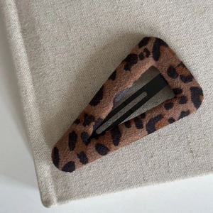 Macro shot of triangular leopard print hair clip with velvet texture and metal BB grip