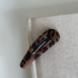 Detailed macro view of leopard print fabric teardrop hair clip with soft velvety texture